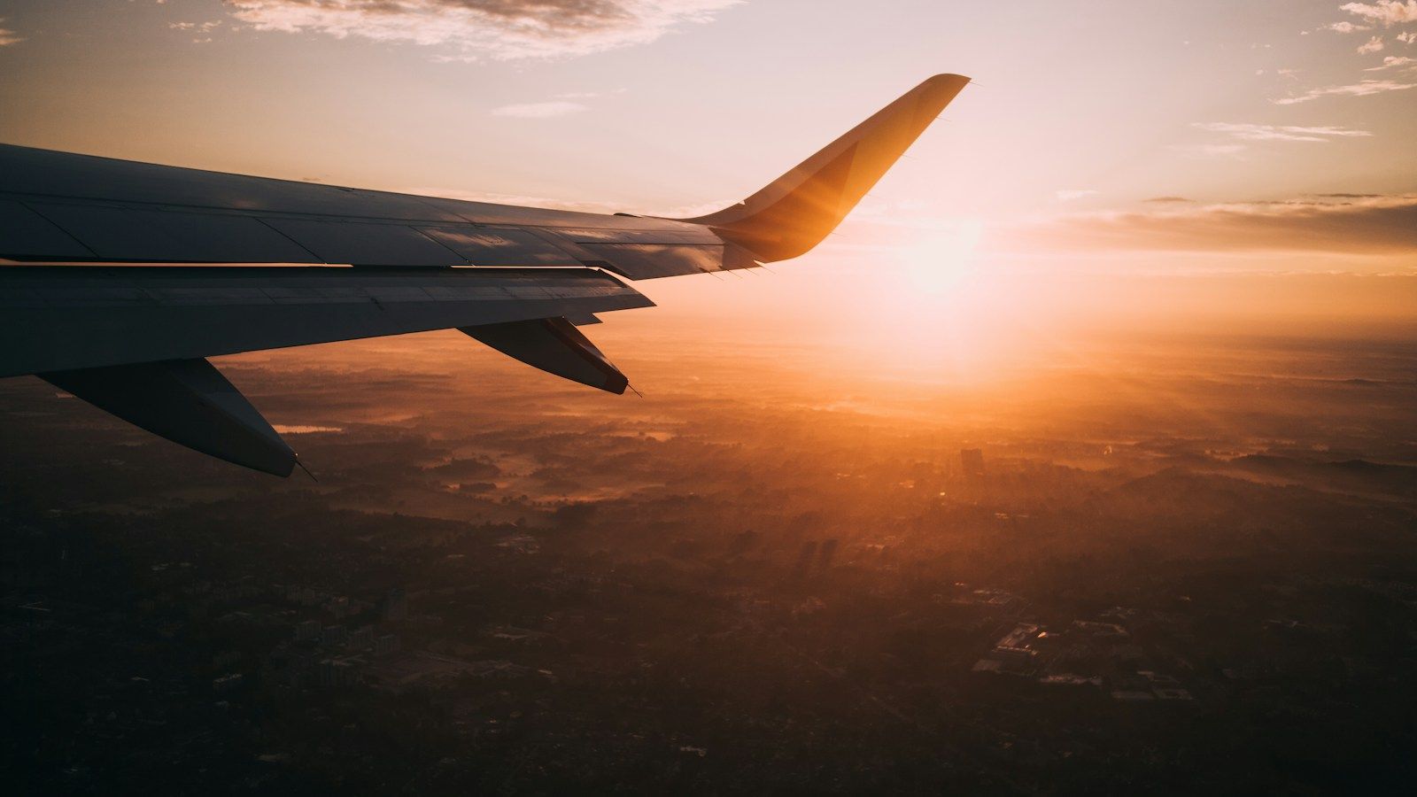 An aircraft wing above the clouds at sunset