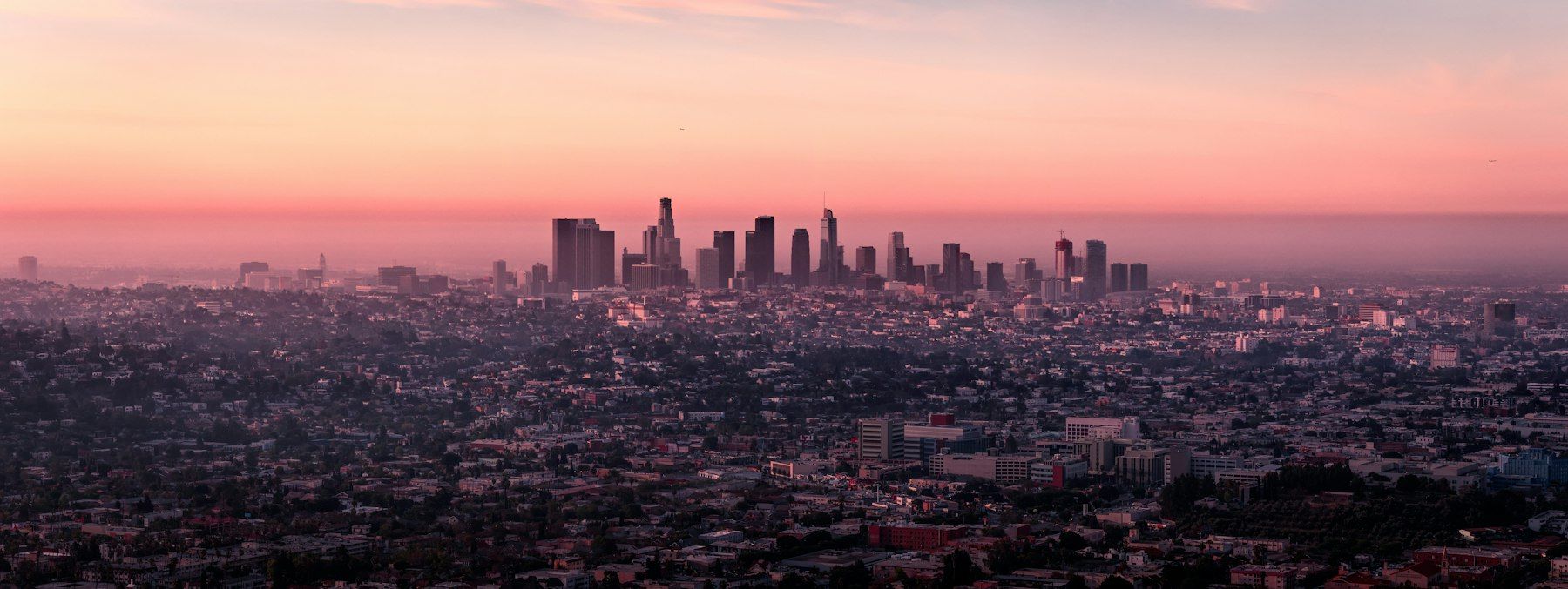 The downtown Los Angeles skyline at dawn under a pink sky